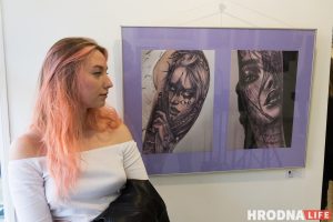 Полина Ситько занимается татуировкой более трех лет. Работает в стиле реализма в черно-белом цвете. На фота она стоит рядом со своими работами