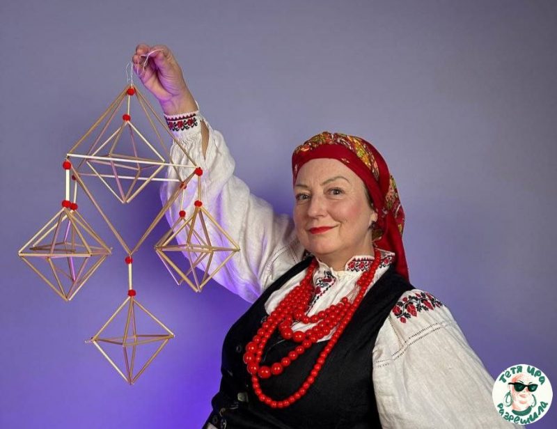 Ирина Новик держит в руках соломенного паука. Соломенный паук может быть ромбическим или пирамидальным, делается из соломки и ниток.